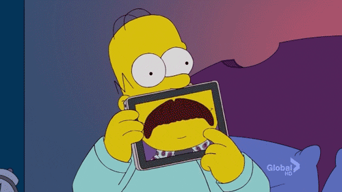 Homer Simpson holding a tablet in front of his mouth and swiping through different mouths