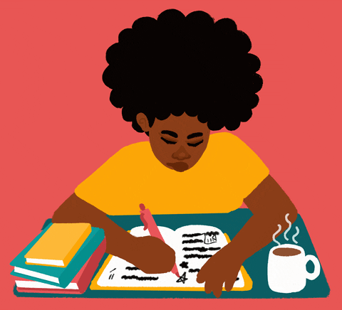 lady with big black hair writing in her book with a cup of coffee and other books on her desk