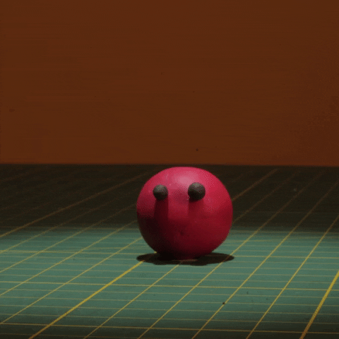 a red blob character with black eyes jumps up and down on a green and yellow cutting board displaying squash and stretch stop motion animation